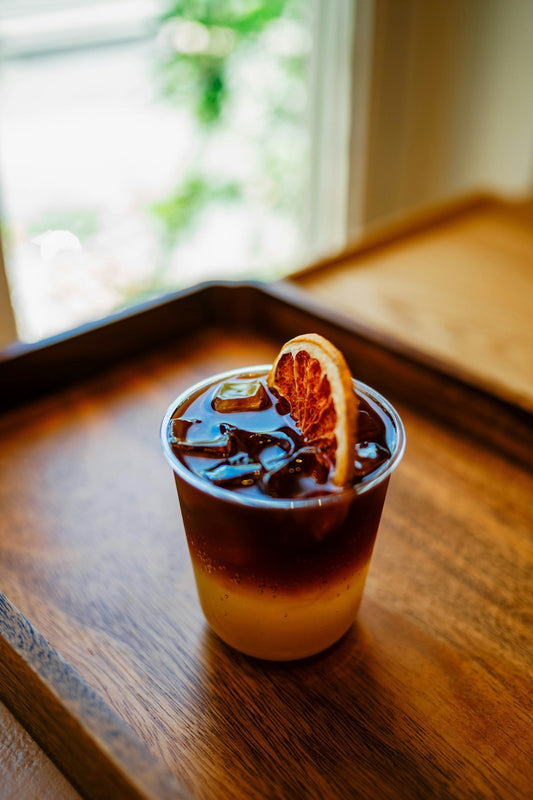 Glas mit Getränk mit Eiswürfeln und Orangenscheibe